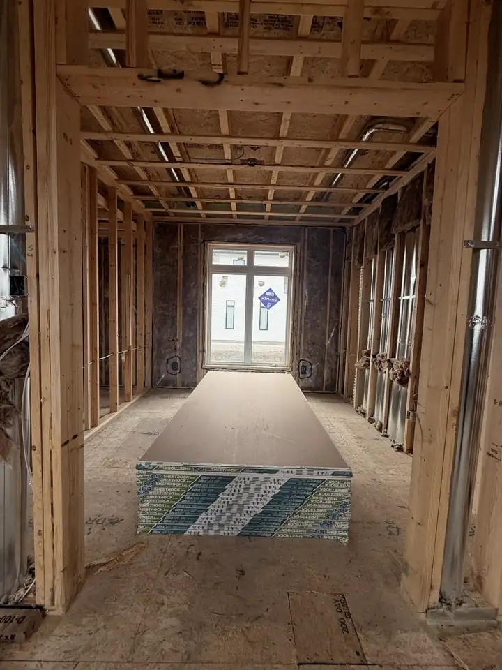 Before: open wood framing, insulation and a stack of drywall sheets in the middle of the bedroom